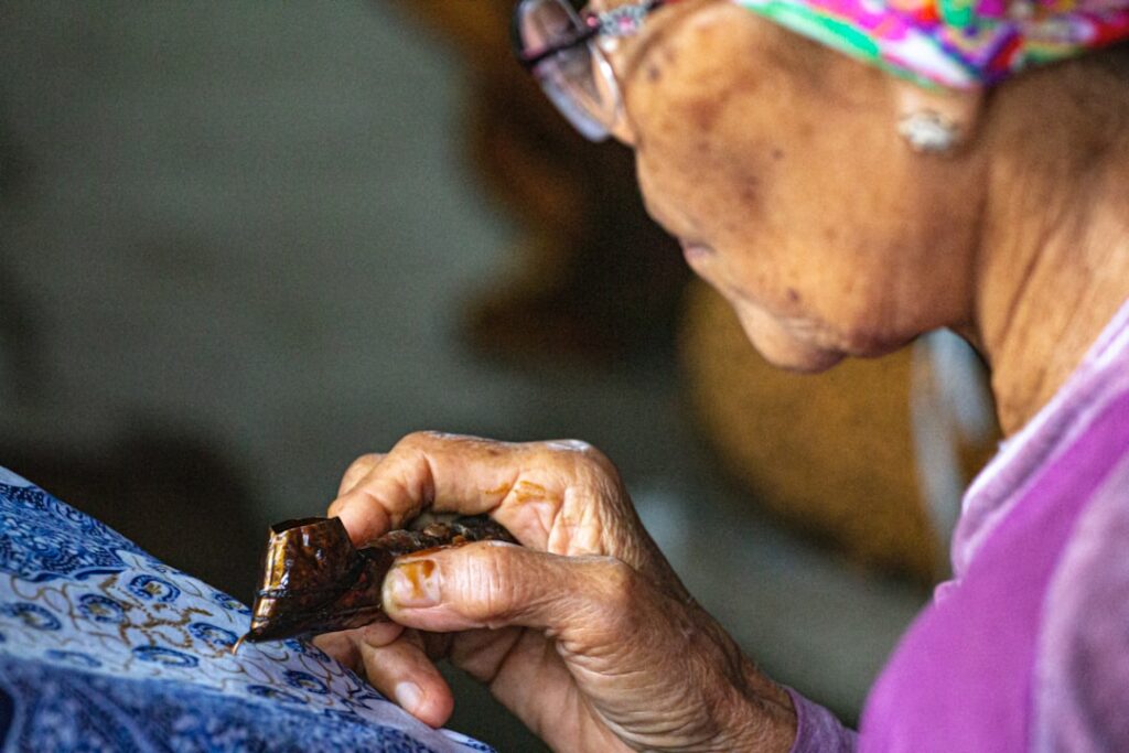 Traditional Indonesian batik artisan using a canting to apply wax to fabric
